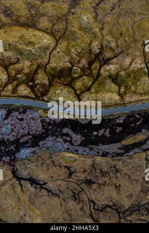 Una vista aerea mostra una strada che passa attraverso paesaggi stupendi in verde kaki, marrone e nero, così insoliti quasi non sembrano reali. Foto Stock