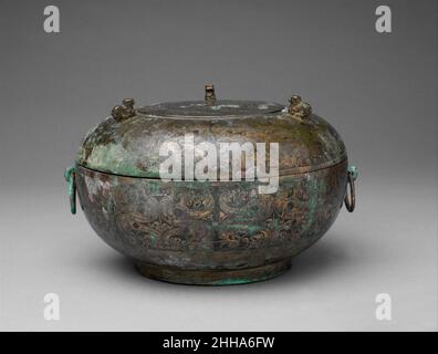 Contenitore per alimenti rituali con coperchio (Dui) ca. 4th secolo a.C. Cina il coperchio di questo contenitore di cibo è abbellito con tre animali che fungono da piedi quando il coperchio è invertito come un vassoio. Draghi accoppiati e ricci rotolanti decorano la superficie del vaso. Le depressioni di fusione nel disegno sono riempite con un pigmento nero fatto di osso char e lacca che aumenta il contrasto tra la composizione e lo sfondo. L’arredamento sontuoso della nave è caratteristico dei bronzi tardivo di Zhou ad est, che in questo periodo erano visti come simboli di ricchezza e di stato piuttosto che semplicemente paraphernalia per solem Foto Stock