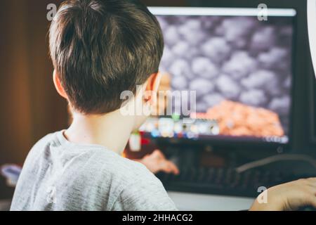 Il ragazzo gioca la minecraft. Giochi per computer a casa. Costruzione sotto forma di gioco. Giochi per bambini e computer. Processo di gioco. Gestione in minecraf Foto Stock