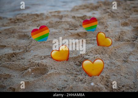 sul mare lgbt e cuori gialli nella sabbia stand Foto Stock