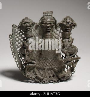 Ciondolo protettivo 15th–19th secolo inferiore Niger Bronze industria questo ornamento semicircolare era probabilmente di proprietà di un capo provinciale alleato al regno del Benin, in quello che è oggi la Nigeria meridionale. Con l'espansione del territorio del regno del Benin, esso ha diffuso le sue tradizioni cortesi tra i popoli etnicamente diversi che sono stati incorporati nella sua struttura politica. I regnanti regionali spesso hanno appropriato e riconfigurato i simboli del potere del Benin per il loro uso a livello locale. In questo esempio, un motivo standard dell'arte reale del Benin, un capo centrale fiancheggiato da due assistenti che sup Foto Stock