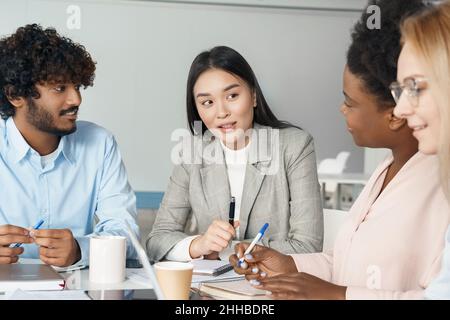 Studenti multietnici diversi che lavorano su un progetto comune seduti alla scrivania in classe Foto Stock