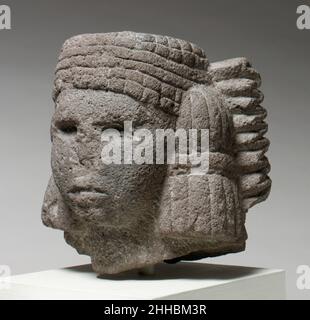 Testa di una divinità dell'acqua (Chalchiuhtlicue) 15th–inizio 16th secolo Aztechi gli Aztechi scolpiscono migliaia di immagini dei loro dei in pietre che vanno dalle pietre greenstones molto apprezzate alla roccia vulcanica ordinaria. Sculture come l'esempio attuale sono state probabilmente allestite in santuari domestici dove sono state adorate in ambienti familiari piuttosto che in cerimonie pubbliche. Le divinità aztec raffigurate frequentemente sono divinità della fertilità, che includono la dea dell'acqua Chalchiuhtlicue ('la gonna di giada') raffigurata qui. Gli elementi identificanti della dea dell'acqua sono il distintivo headdress che consiste di multiplo (i Foto Stock