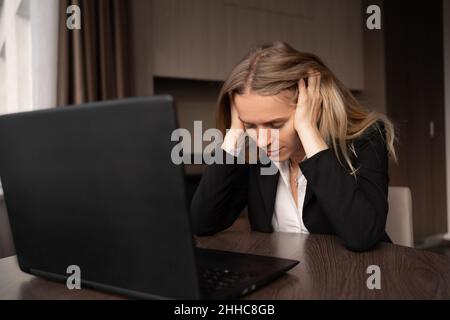 Donna malata che lavora al computer portatile con mal di testa stanco in ufficio a casa, emicrania e mestruazioni, salute medico consultazione, radiazioni elettromagnetiche Foto Stock