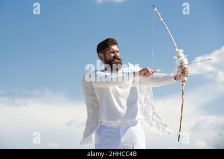 San Valentino. Amore e romanticismo. Pazzo angelo Cupido puntando con la freccia d'amore con spazio copia sul cielo. Foto Stock