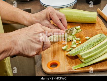 La donna sta tagliando zucchine per cucinare a casa utilizzando la ricetta da Internet Foto Stock