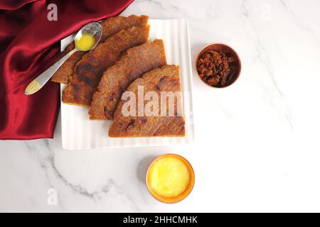 Roti dolci a base di farina di riso, gelate e ghee. gur ki roti. gur ki roti, bhakri gelatinoso, roti meethi gud ki cotto in foglia di banana. Cibo invernale Foto Stock