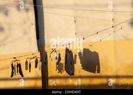 Lavanderia che asciuga al sole del mattino di fronte ad una parete di ocra. Jiashan, Cina Foto Stock