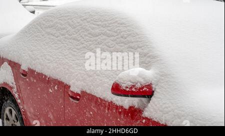 Auto rossa coperta di neve durante la tempesta nevosa pesante Foto Stock