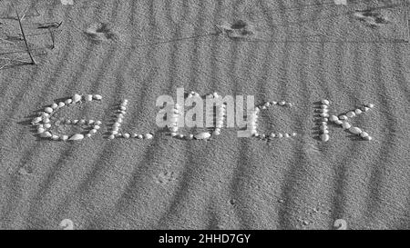 Con conchiglie disposte simbolo felicità sulla spiaggia del Mar Baltico nella sabbia. In bianco e nero. Desideri per la vacanza e la vita. Foto Stock