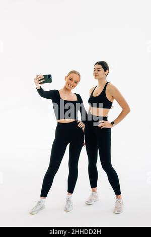 Due donne si incontrano in palestra, facendo foto selfie Foto Stock