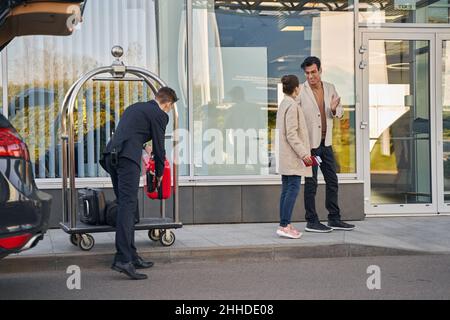 L'operatore dell'aeroporto scarica il bagaglio di coppia dal carrello Foto Stock
