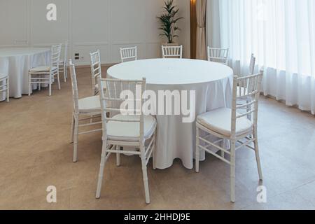 Concetto di banchetto nuziale. Sedie e tavolo rotondo per gli ospiti,  servito con cutler e, fiori e stoviglie e coperto da una tovaglia Foto  stock - Alamy