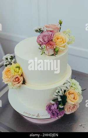 Torta nuziale in un ristorante bianco decorato con fiori freschi Foto Stock