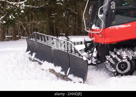 Il secchio di un aratro da neve sulle piste, in piedi nella foresta in inverno. Foto Stock