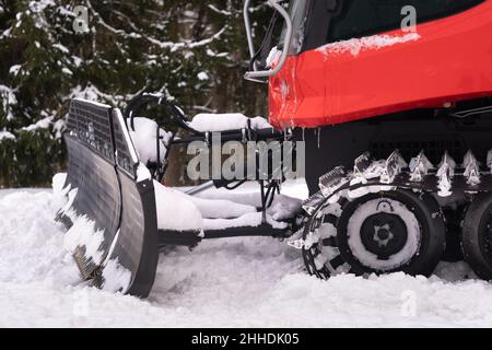 Il secchio di un aratro da neve sulle piste, in piedi nella foresta in inverno. Foto Stock