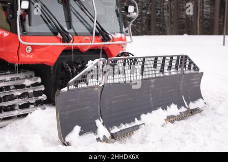 Il secchio di un aratro da neve sulle piste, in piedi nella foresta in inverno. Foto Stock