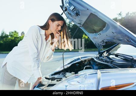 La donna confusa esamina il motore dell'auto Foto Stock