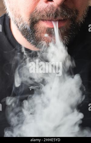 Primo piano di una bocca che soffia fumo grigio di sigaretta. Foto Stock