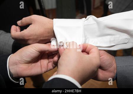 Primo piano del braccio dello sposo vestito dai suoi migliori amici. Messa a fuoco soft Foto Stock