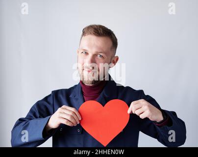 San Valentino o tema d'amore: Uomo tecnico, appaltatore, supervisore o ingegnere indossando uniforme blu tenendo rosso carta forma cuore. Romanticismo o concetto di relazioni. Immagine di alta qualità Foto Stock