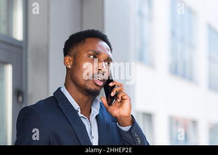 African American uomo d'affari maschio arrabbiato parlare al telefono cellulare fuori. Uomo d'affari che fa una telefonata all'aperto. Nervoso pazzo professionale conversatio Foto Stock