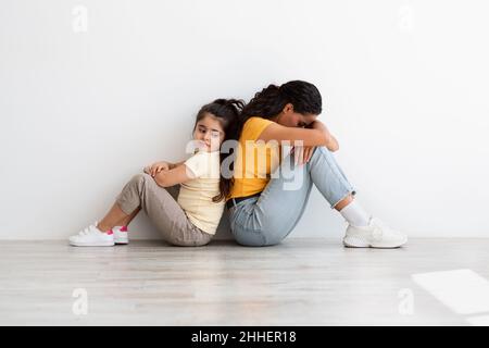 Sfide della maternità. Mamma sconvolto seduta Back to Back con figlia dopo argomento Foto Stock