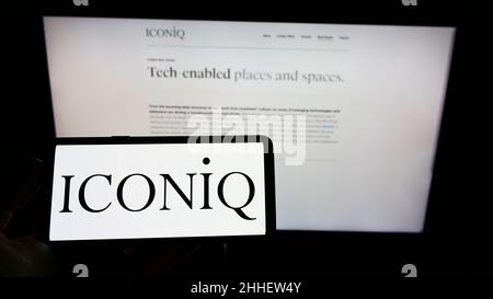 Persona che detiene il cellpohone con il logo della società di investimento statunitense ICONIQ Capital LLC sullo schermo di fronte al sito web aziendale. Mettere a fuoco sul display del telefono. Foto Stock