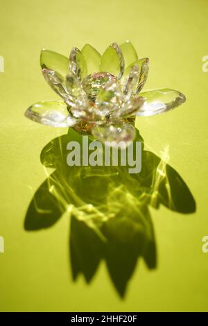 Bellissimo fiore di cristallo di loto su un tavolo verde soleggiato. Foto Stock