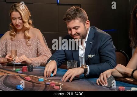Giovane uomo bearded che fa le scommesse mentre gioca a poker nel casinò Foto Stock