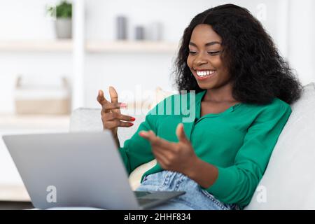 Chatty afroamericana donna che ha una videochiamata, utilizzando un portatile Foto Stock