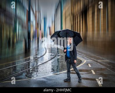 Uomo con ombrello nella città piovosa Foto Stock