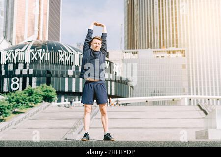 Giovane atleta che corre su e giù sulle scale della città in estate sulla corsa mattutina, sullo sfondo urbano strada della città. Allenamento sportivo. Fitness cardio Foto Stock