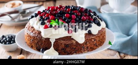 Torta con frutti di bosco freschi e panna su vecchio sfondo di legno. Messa a fuoco selettiva. Foto Stock