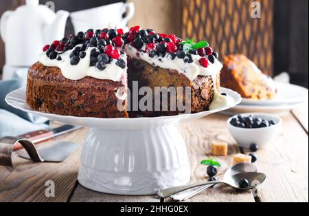 Torta. Torta di natale fatta in casa con frutta secca decorata con crema di vaniglia dolce, bacche fresche e crema su vecchio sfondo di legno. Messa a fuoco selettiva. Foto Stock