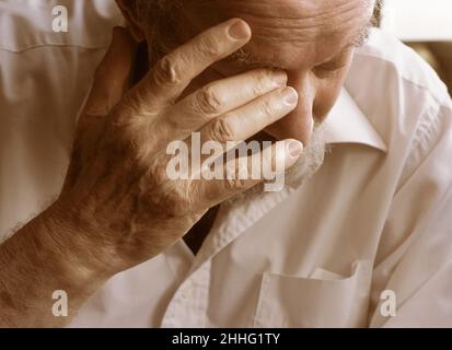 Invecchiamento ansia ed emozione per la salute. Uomo anziano da solo con la mano in faccia. Ritratto di un caucasico maturo e stanco serio anziano nel profondo del pensiero. Foto Stock