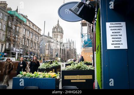 Un cartello all'esterno di un negozio sul Royal Mile di Edimburgo che dice "è necessario indossare una copertura facciale", in quanto le coperture facciali sono ancora obbligatorie in negozi, bar, ristoranti e sui trasporti pubblici, nonostante le restrizioni finali messe in atto in risposta alla variante di Omicron che attraversa la Scozia sia allentata. Data foto: Lunedì 24 gennaio 2022. Foto Stock