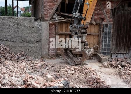 un luogo di costruzione con mattoni rotti sul pavimento ed il secchio grande di metallo di un scavatore Foto Stock