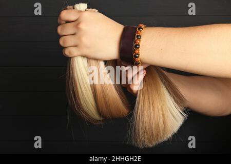 La mano maschio tiene le sezioni di capelli per l'estensione. Foto Stock