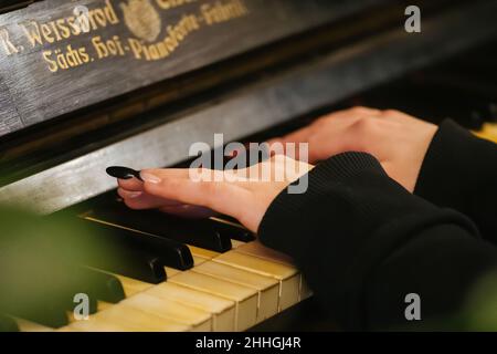 Belle mani con lunghe dita di una ragazza con unghie laccate nere che suonano un vecchio pianoforte Weissbrod Eisenberg Foto Stock