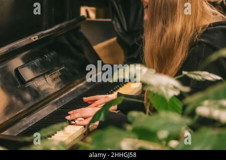 Belle mani con lunghe dita di una ragazza con unghie laccate nere che suonano un vecchio pianoforte Weissbrod Eisenberg Foto Stock