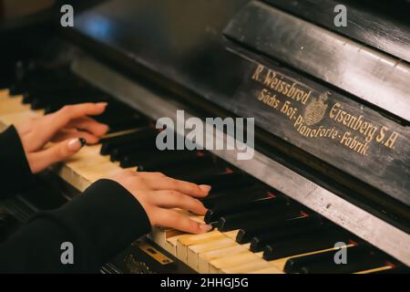 Belle mani con lunghe dita di una ragazza con unghie laccate nere che suonano un vecchio pianoforte Weissbrod Eisenberg Foto Stock