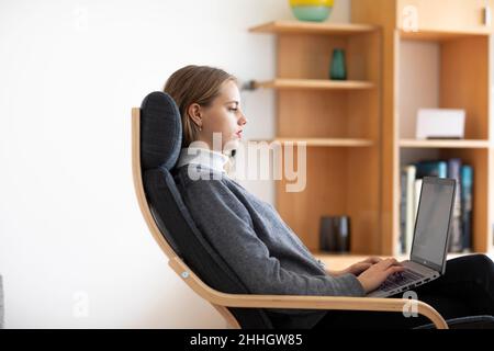 Profilo di una giovane donna che usa un portatile a casa Foto Stock