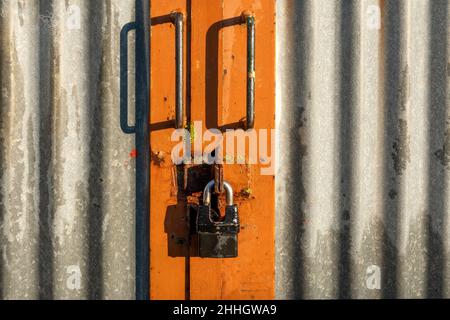 Pannelli in ferro corrugato nella porta dell'edificio agricolo con maniglie e lucchetto Foto Stock