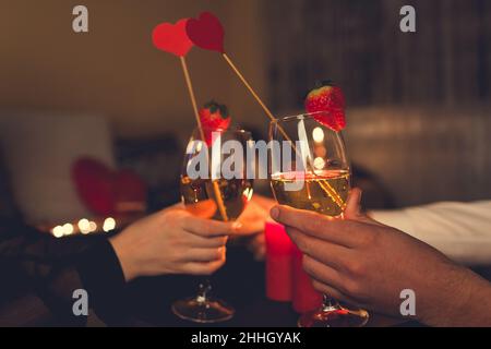 San Valentino coppia in amore calici che bevono vino con fragole e decorazione a forma di cuore con cena romantica con candele Celebre Foto Stock
