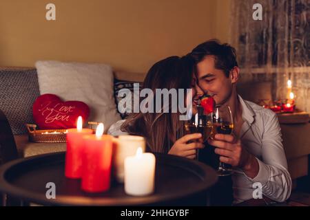 Giovane San Valentino coppia in amore calici che bevono vino con fragole cena romantica con candele festeggiavano a casa di notte Foto Stock
