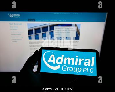Persona che tiene smartphone con il logo della compagnia di assicurazioni britannica Admiral Group plc sullo schermo di fronte al sito web. Mettere a fuoco sul display del telefono. Foto Stock