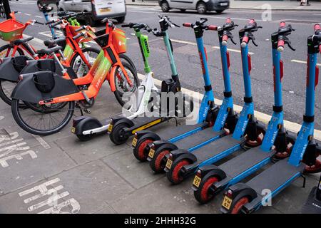 Il 21st gennaio 2022 a Londra, Regno Unito, Dott eScooters si è schierato sul marciapiede accanto a quelle di altre società di condivisione di biciclette e eScooter. Un sistema di condivisione scooter è un servizio di trasporto condiviso nel quale gli scooter elettrici, detti anche e-scooters, sono messi a disposizione per il noleggio a breve termine. Gli e-scooters sono solitamente ancorkless, il che significa che non hanno una sede fissa e sono lasciati fuori e prelevati da determinate posizioni nell'area di servizio. Foto Stock