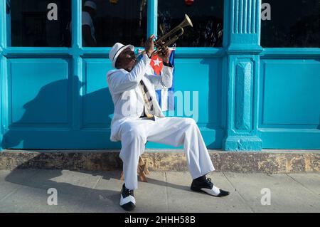 Il musicista cubano suona la tromba accanto ad una bandiera cubana in una strada a Old Havana Foto Stock