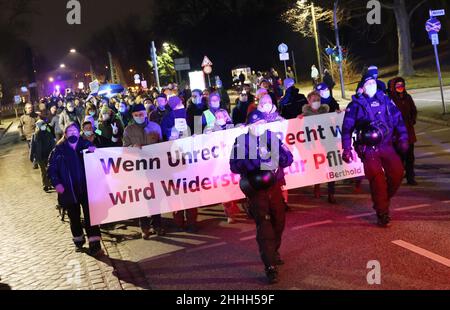 24 gennaio 2022, Schleswig-Holstein, Lübeck: Ufficiali di polizia accompagnano i manifestanti a Lübeck. I manifestanti portano una bandiera con l'iscrizione: 'Quando l'ingiustizia diventa giusta, la resistenza diventa un dovere' durante una dimostrazione contro le misure di Corona. Foto: Christian Charisius/dpa Foto Stock